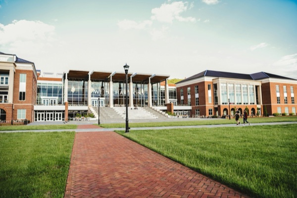Brick university buildings and a student union around a green lawn with a brick path