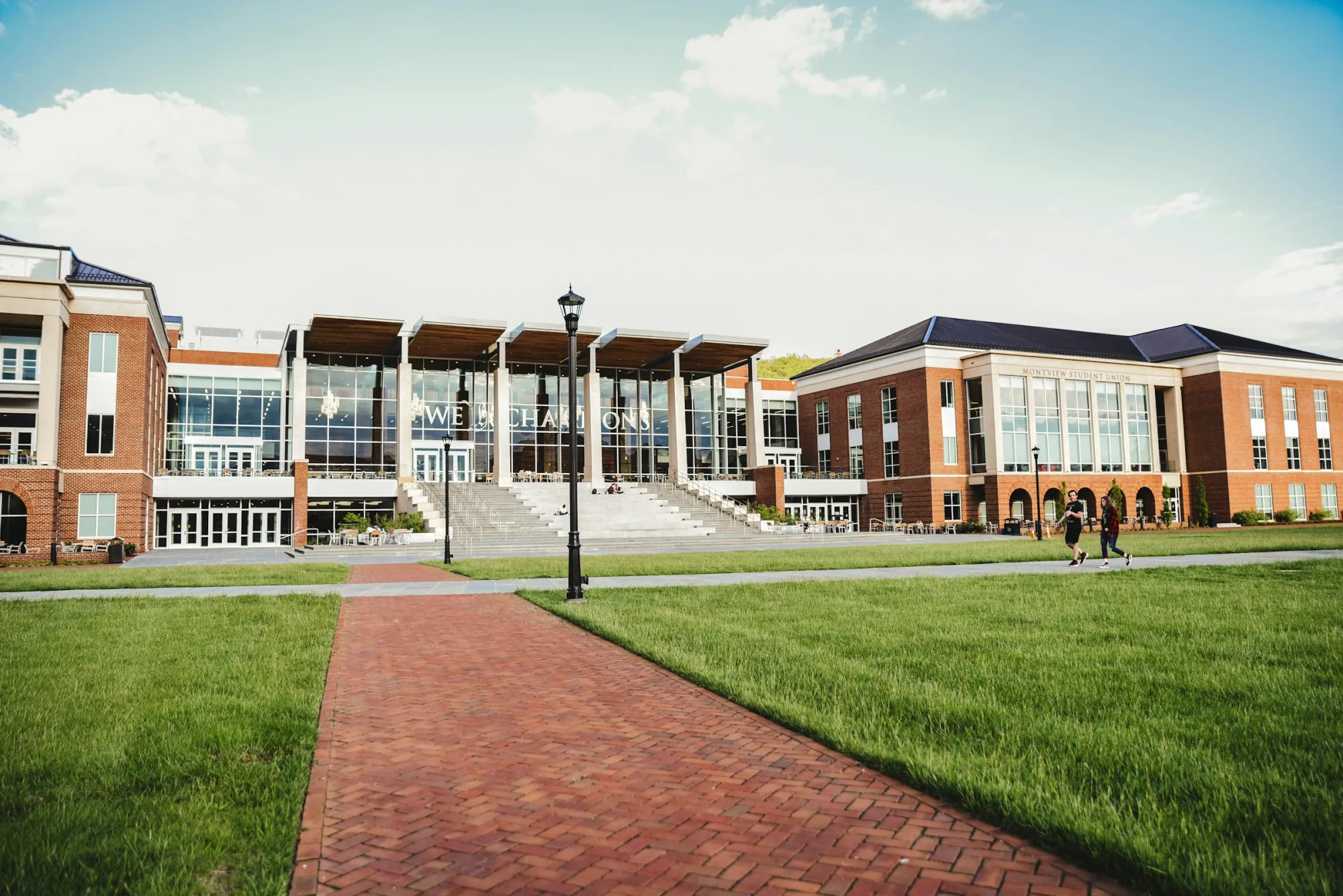 Brick university buildings and a student union around a green lawn with a brick path
