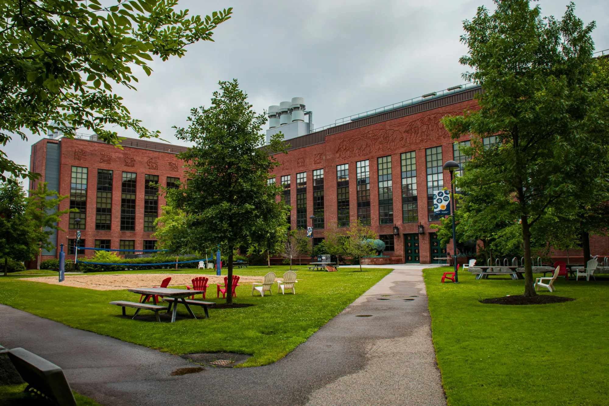 Red brick university building and a green campus quad with picnic tables